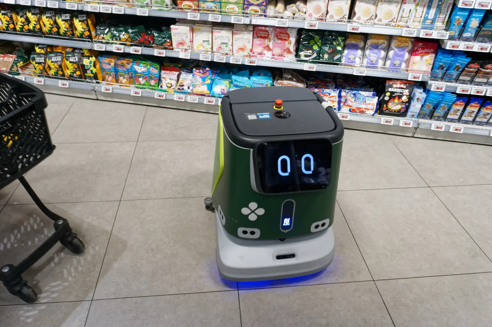 Autonomer Scheuersaugroboter fährt allein durch den Gang eines Supermarkts